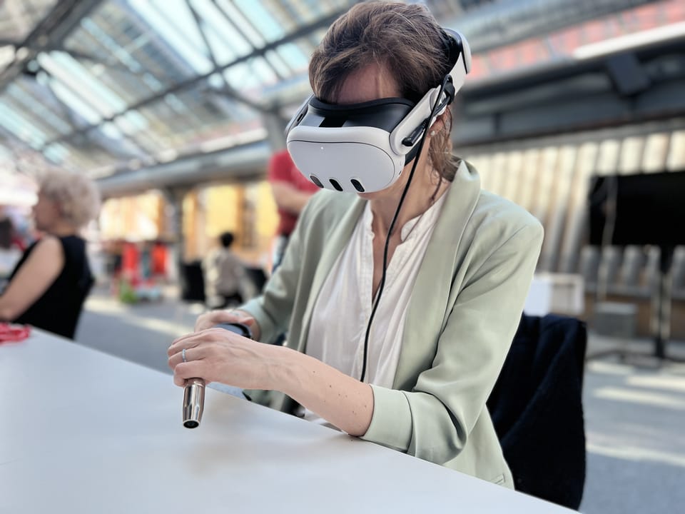 Frau mit VR-Brille hält einen Schweißbrenner-Controller in einer Glashalle