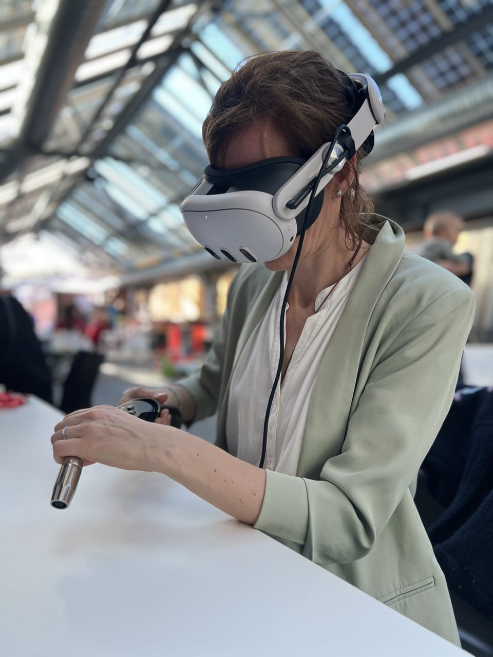 Frau mit VR-Brille übt am Tisch mit einem Brenner-Controller, Hochformat